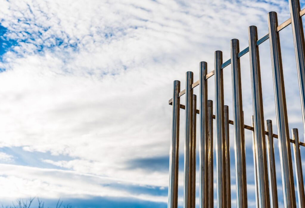 Upward view of tall aluminum fence posts extending toward a clear blue sky