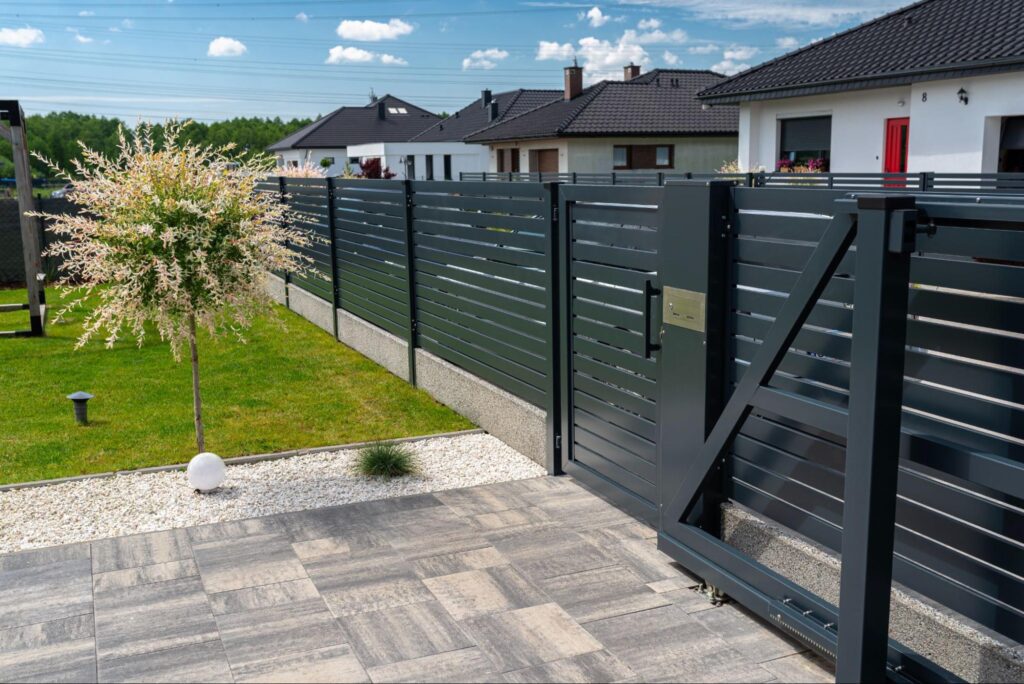 A modern steel fence is used as a front gate to a house.